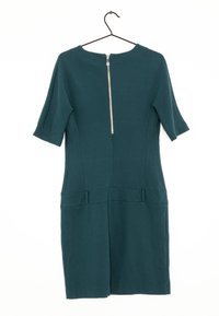 Teal klänning med korta ärmar, figurnära design, framfickor och dragkedja bak. Tillverkad av ett slätt tyg i en solid färg.