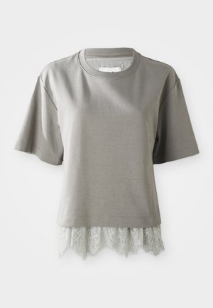 Īsām piedurknēm, gaiši pelēka T-kreklu no mīksta materiāla, ar mežģīņu apdari apakšā un viļņainām malām. Tekstūrēta mežģīne piešķir detaļas.