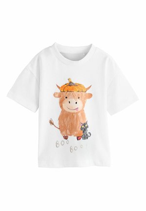 White short-sleeve t-shirt featuring an illustration of a brown Highland cow wearing a pumpkin hat, alongside a black cat, with "Boo Boo!" text.