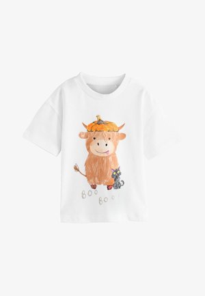 Hvid t-shirt med et tegneserie-illustration af en højlandsko med et græskarhat, der står ved siden af en sort kat, med teksten "Boo Boo!" trykt nedenfor.