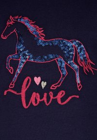 Tessuto blu navy con un design di cavallo rosso e blu adornato da paillettes. Cuori ricamati in rosa e oro e la parola "amore" in corsivo rosso.