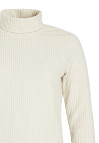Jersey de cuello alto acanalado de color crema con mangas largas, mostrado desde el pecho hacia arriba.