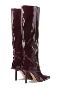 Stivali alti in pelle verniciata bordeaux con punta affusolata e tacco a stiletto, caratterizzati da una superficie liscia e un design minimalista.