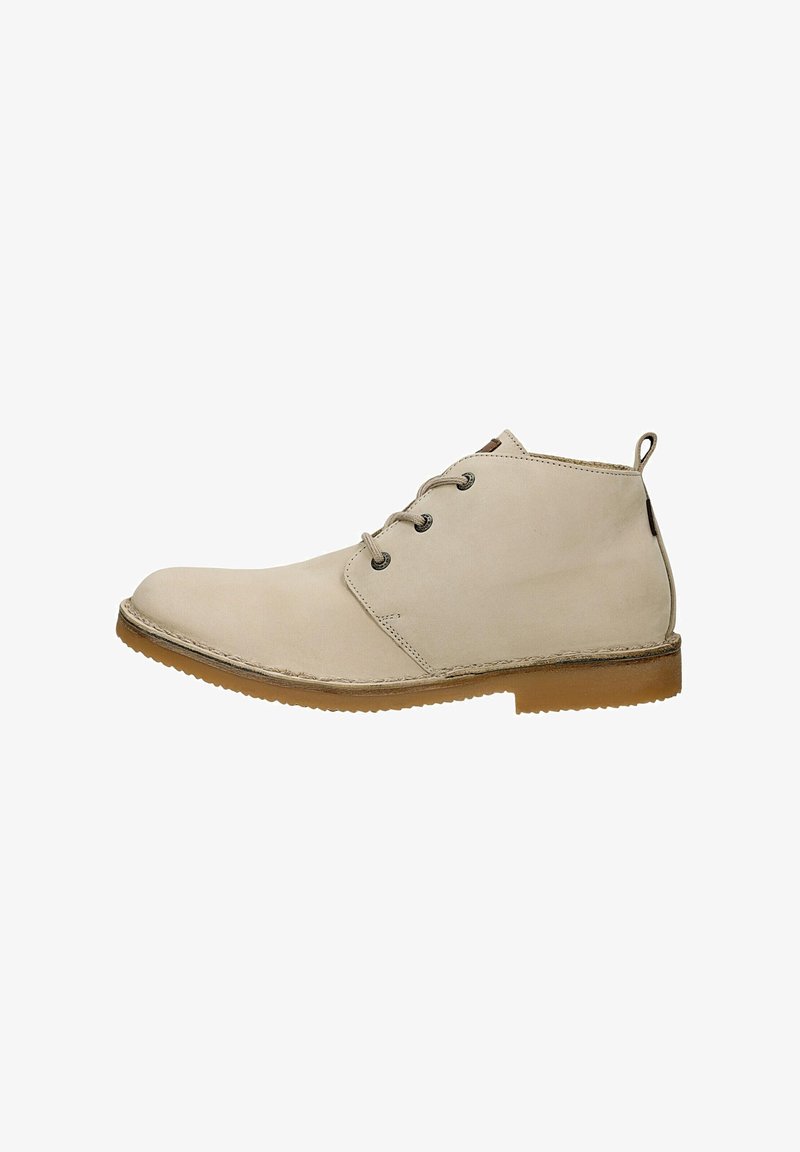 Bottes chevilles en cuir beige avec un bout arrondi, deux œillets métalliques pour les lacets, et une semelle en caoutchouc. Texture lisse avec un design simple.