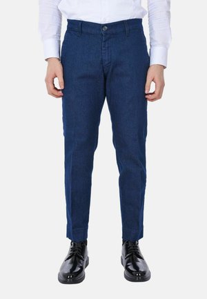 Pantaloni blu navy realizzati in tessuto denim, con un design slim fit, chiusura con bottone frontale e orlo semplice. Abbinati a scarpe nere.