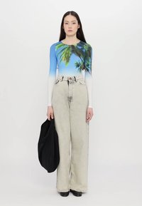 Long-sleeve top featuring a blue gradient with palm tree print, paired with high-waisted, loose-fitting light gray denim jeans and black bag.