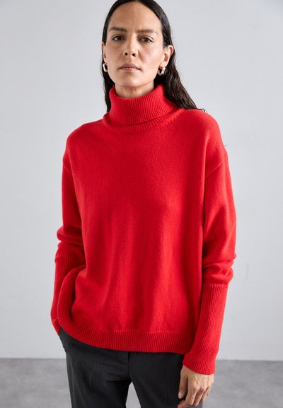 Red turtleneck sweater made of textured fabric, featuring ribbed accents at the collar and sleeves, relaxed fit, and dropped shoulders.