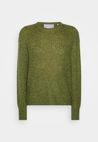 Grön stickad tröja med rund halsringning, långa ärmar och en strukturerad tygkvalitet. Lappen vid nacken har varumärket "JJXX."