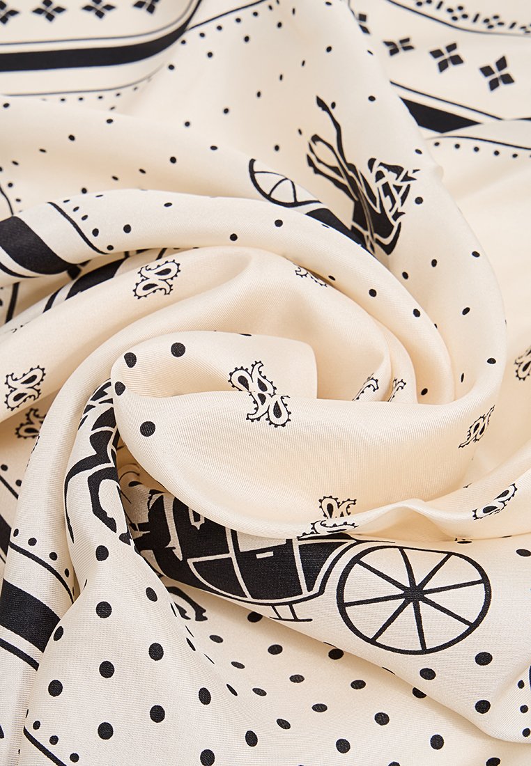 Tissu crème avec des motifs noirs, comprenant des points et des dessins détaillés de carrioles. Le matériau semble lisse et léger, avec une texture douce.