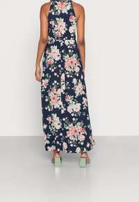 Kukallinen maksimekko, jossa on tummansininen tausta pinkeillä ja vihreillä ruusuilla. Halterneck-muotoilu, muotoiltu vyötärö ja ilmava hame, jossa on sivurei'itykset.