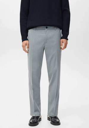 Pantalones grises a rayas con una tela ligera, que presentan un corte ajustado, frente plano y un cierre con un solo botón. Combinados con un suéter oscuro.