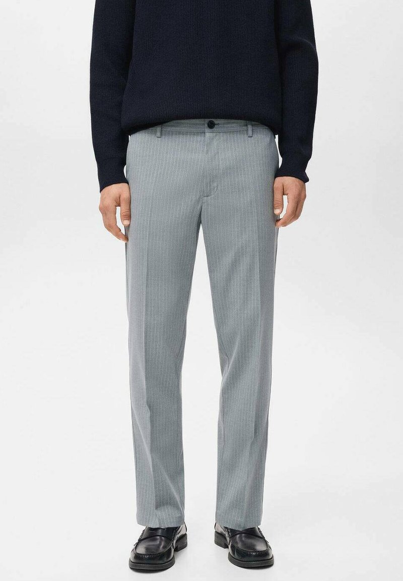Pantalones grises a rayas con una tela ligera, que presentan un corte ajustado, frente plano y un cierre con un solo botón. Combinados con un suéter oscuro.