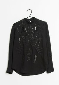 Top nero a maniche lunghe con dettagli intricate in paillettes e perline, accenti a strisce testurizzate sulle maniche e un collo alto.