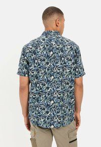 Korte mouw shirt met een donker marineblauwe achtergrond en een levendig loofpatroon in groene en blauwe tinten. Relaxte pasvorm met een traditionele kraag.