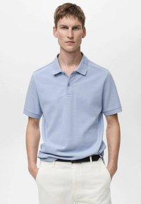 Vaaleansinisessä polo-paidassa on kauluspääntie, kahden napin suljenta ja lyhyet hihat. Sujuva pinta, istuva malli, käytetään valkoisten housujen kanssa.