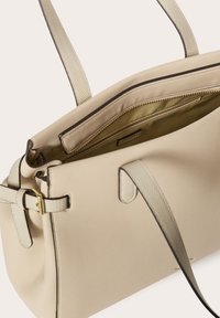 Borsa tote in pelle beige con manici texturizzati e hardware dorato; presenta una tasca interna con zip e una fodera chiara. Caratterizzata da un design minimalista.