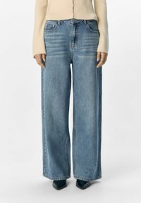 Jeans a gamba larga blu chiaro in denim con vita alta e due tasche frontali, caratterizzati da una finitura liscia e texture minima.