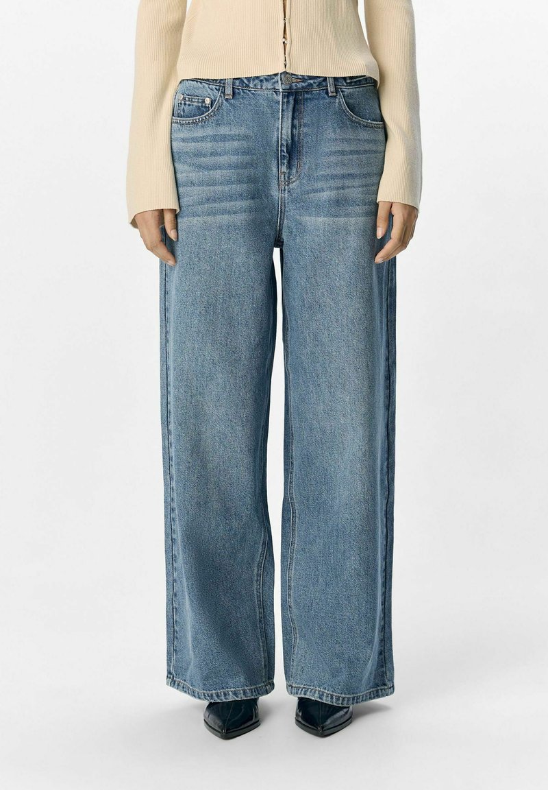Jeans a gamba larga blu chiaro in denim con vita alta e due tasche frontali, caratterizzati da una finitura liscia e texture minima.