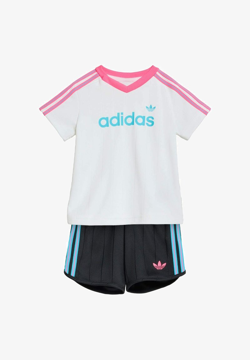 Bijela Adidas majica kratkih rukava s ružičastom kragnom i prugama, u kombinaciji s crnim kratkim hlačama s ružičastim i plavim prugama te Adidas logom.