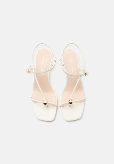 Witte sandalen met open teen, dunne enkelbandjes, gouden gesp, ontwerp met vierkante neus en gouden bolvormige versiering op de voorste bandjes.