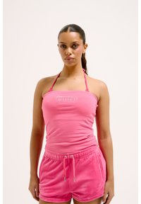 Pink halter top with "Juicy" text in rhinestones and matching pink velvet shorts with an elastic waistband and drawstring.