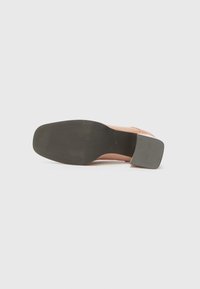 Pink high heel shoe with a smooth upper, a textured black rubber sole, and a square heel. Features a flat tip and minimal detailing.