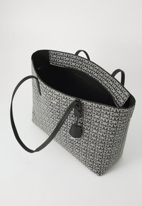 Τσάντα tote σε μαύρο και λευκό καμβά με επαναλαμβανόμενο μοτίβο λογοτύπου, μαύρες δερμάτινες λαβές και κλεισίματα στην κορυφή. Ο εσωτερικός χώρος διαθέτει μία τσέπη.