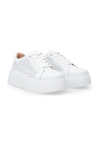 Weiße Sneaker mit einem durchbrochenen Obermaterial, flachen Schnürsenkeln und einer dicken weißen Gummisohle. Glatte Textur mit Akzenten in einem hellen Beige.