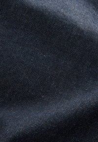 Donkerblauwe stof met een subtiele textuur, waarop een diagonale weefstructuur te zien is, met kleine, lichtere stippen verspreid over de hele stof.