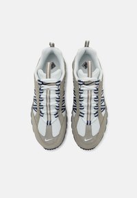 Sneakers cu un superior din plasă albă, accente de suede gri și dungi albastre închise. Au vârf rotunjit și o talpă texturată pentru tracțiune.