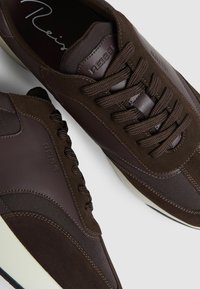 Pruunid tossud, mis on valmistatud segatud nubuk- ja võrgumaterjalidest, paksude paeltega, ümarate varvastega ja valge kummist tald.