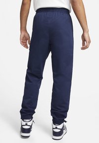 Pantalones jogger azul marino con cintura elástica, puños ajustados y bolsillo cargo lateral. Textura suave, adecuados para un uso casual.