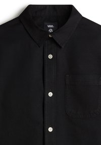 Camicia nera con bottoni, caratterizzata da un colletto a punta, bottoni bianchi, una tasca sul petto e una leggera texture. Etichetta del marchio visibile all'interno del colletto.