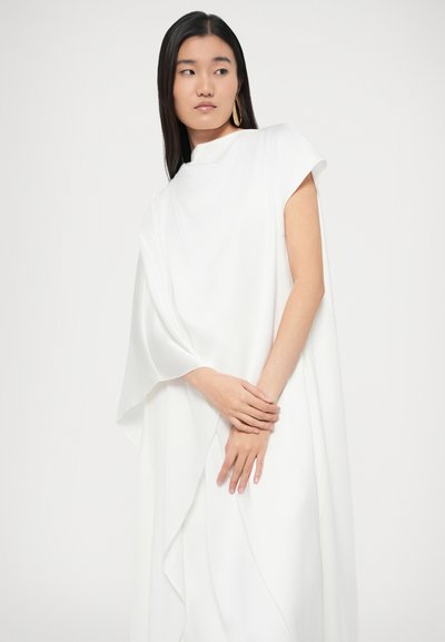 Bijela lepršava haljina s visokim izrezom i kratkim rukavima. Ima preklopljeni dizajn s mekanom teksturom. Jednostavan, eleganciji kroj s minimalnim detaljima.