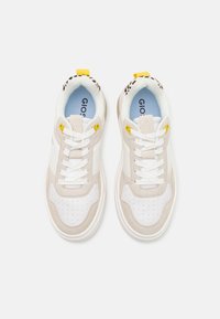 Sneakers with a white upper, beige suede accents, and yellow hardware. Features include perforated toe design and a light blue insole.