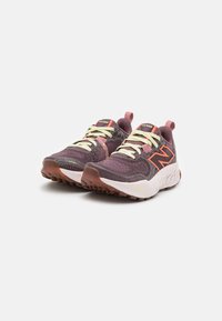 Scarpe sportive viola e grigie con tomaia in rete, intersuola bianca e suola in gomma. Caratteristiche includono lacci gialli e un logo arancione a contrasto.