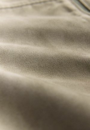 Beige stof met een zachte, gestructureerde oppervlakte en subtiele glans, met gladde plooien en een uniform patroon.