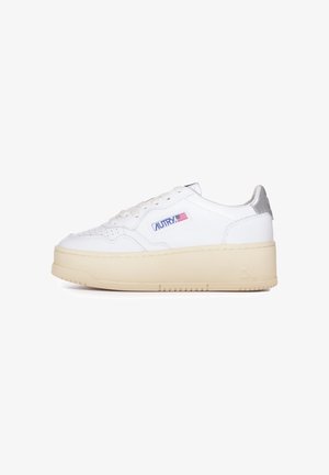Sneaker in pelle bianca con dettagli perforati, linguetta imbottita e suola a piattaforma di un beige chiaro. Presenta un inserto in metallo argentato sul tallone e accenti con logo.
