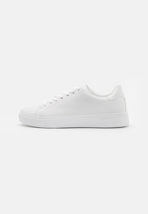 White sneakers with a smooth synthetic upper, round toe, six eyelets for laces, and a low-profile rubber sole with textured detailing.