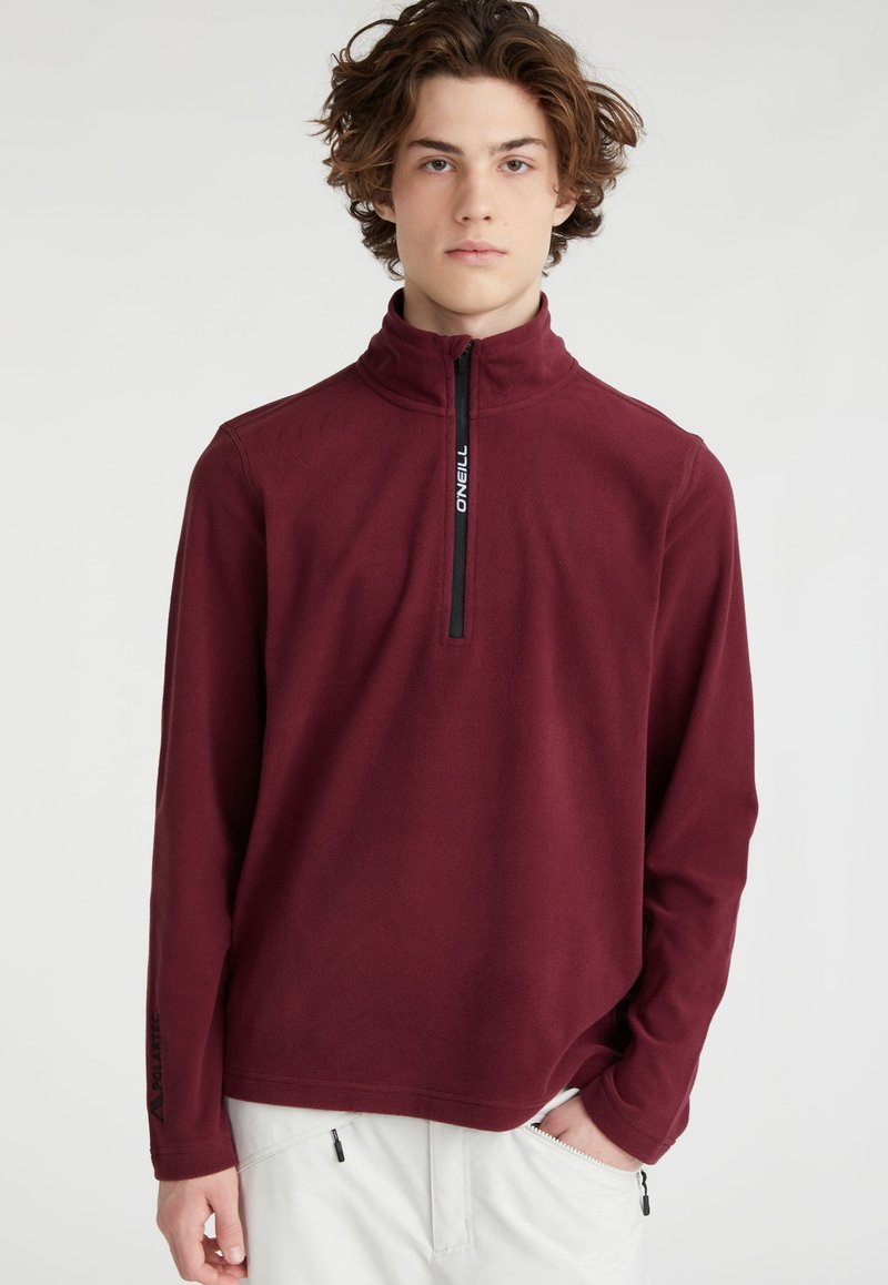 Pull-over bourgogne avec un col montant, demi-zip à l'avant et tissu texturé ; présente un branding noir sur la fermeture éclair et la manche.