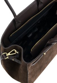 Bruine suède totebag met leren accenten, gouden rits en stoffen voering met logopatroon. Binnenin een ritsvak.