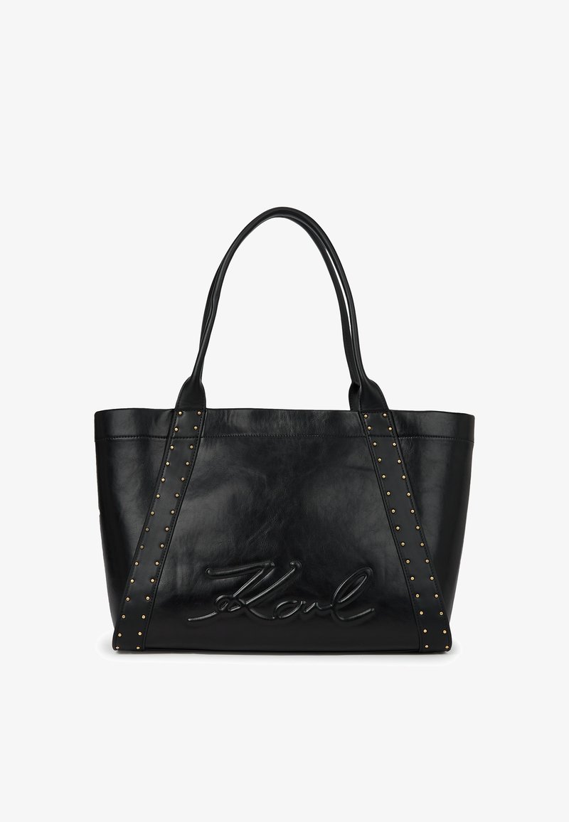 Čierna kožená taška cez rameno s dvojitými ušami, zlatými ozdobnými cvočkami na popruhoch a embosovaným podpisom "Karl" na prednom paneli.