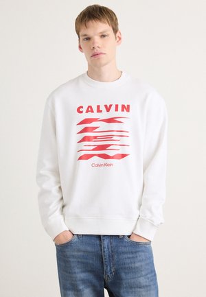 Hvid sweatshirt med et rødt grafisk design med teksten "CALVIN" og "Calvin Klein." Den har ribbede manchetter og crew neck-stil.