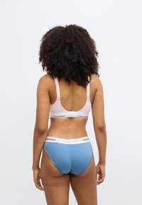 Ροζ σουτιέν με ρυθμιζόμενους ιμάντες και λευκή ζώνη με λογότυπο, σε συνδυασμό με ανοιχτό μπλε ψηλόμεσο εσώρουχο με λευκή ελαστική ζώνη μέσης.