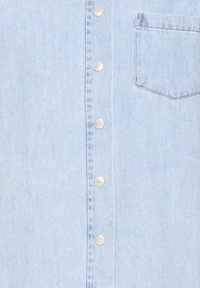 Chemise en denim bleu clair avec fermeture à boutons sur le devant, boutons argentés et une poche poitrine unique, au design épuré et classique.