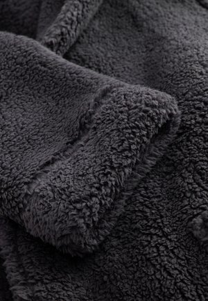 Mørkegråt fleece-stof med en blød, tekstureret overflade og en tyk, fluffy fornemmelse. Har en glat kantdetalje langs manchetterne.