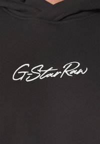 Felpa nera con cappuccio caratterizzata da una texture a coste e un logo "GStarRaw" ricamato in bianco sulla parte anteriore. Design del cappuccio senza hardware visibile.