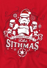 Camiseta roja con un diseño gráfico en blanco que presenta stormtroopers con sombreros de Papá Noel, copos de nieve y texto que dice "Ya empieza a parecerse mucho a SITHMAS."