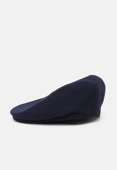 Casquette plate en laine marine avec une texture douce, couronne arrondie et visière légèrement allongée à l'avant. Présente des détails de couture discrets sur les côtés.