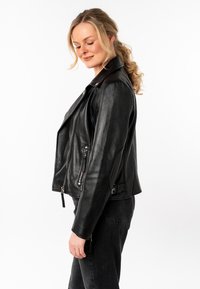 Giubbotto in pelle nera da motociclista con tasche con zip, fronte asimmetrico e texture liscia. Presenta un colletto classico e accenti laterali.
